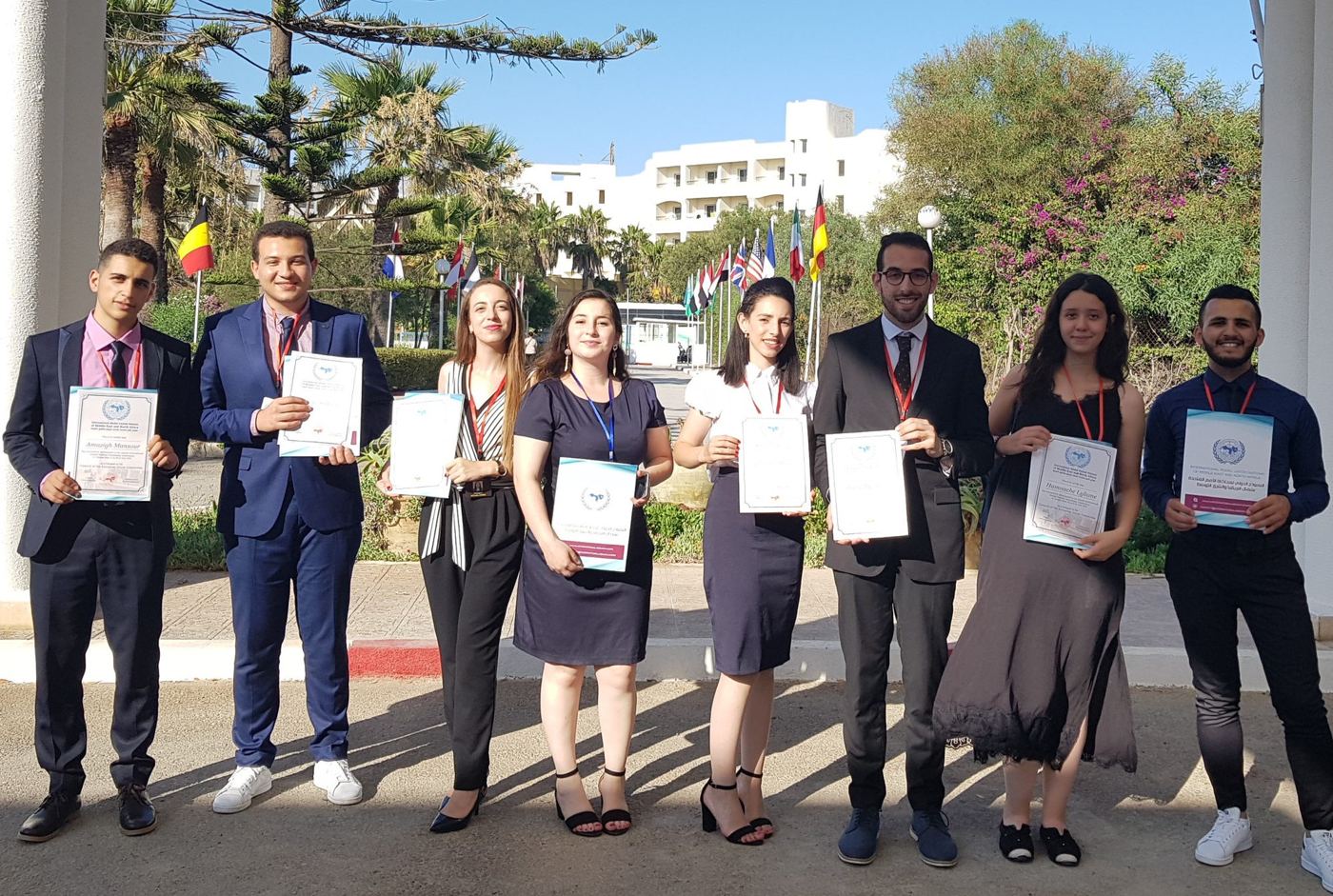 Graduates of a diplomatic training holding their certificates outdoors