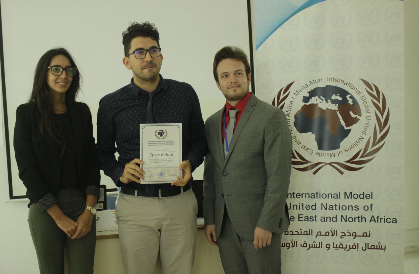 MENAMUN participants holding a certificate in front of the MENAMUN banner